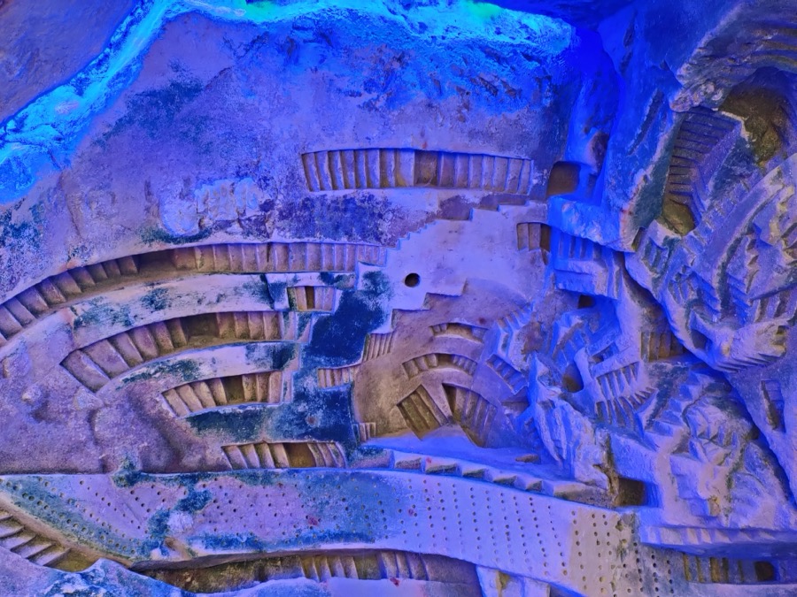 Une galerie troglodyte éclairée de bleu, creusée dans le tuffeau.