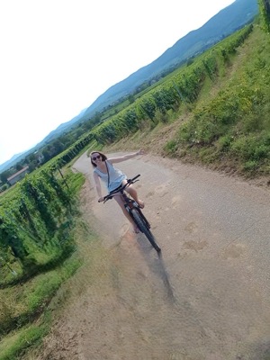 Une cycliste sur un chemin bordé d’arbres, vue de dessus.